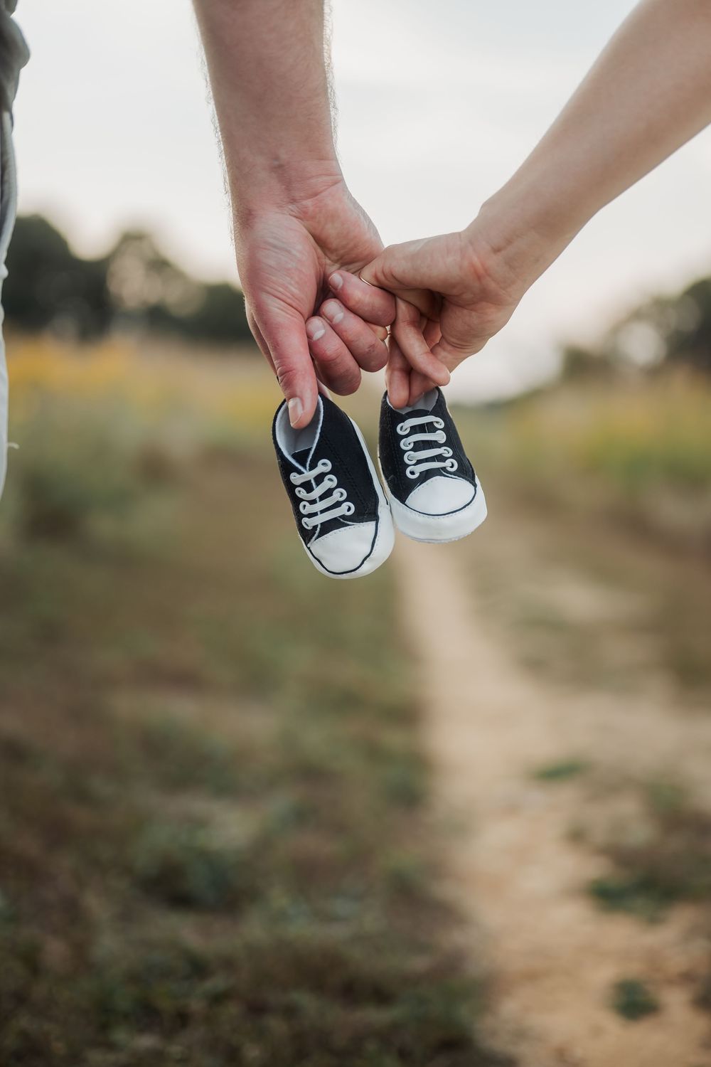 Tiny baby shoes held against blurred natural background.