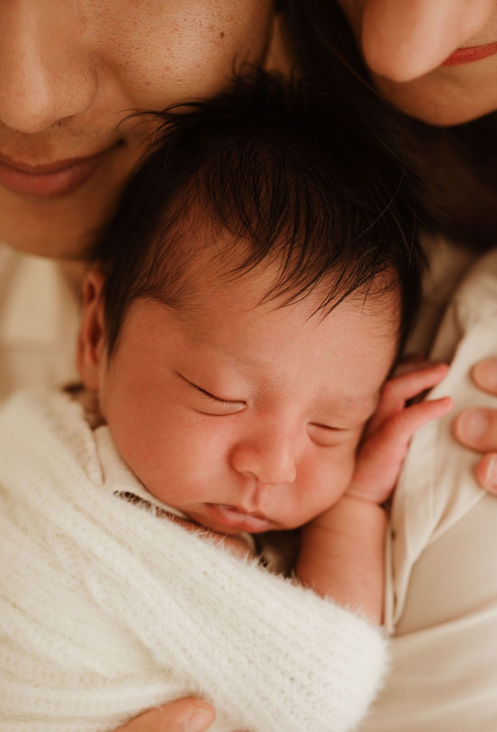 Close-up portrait of peaceful sleeping newborn baby wrapped in white blanket.