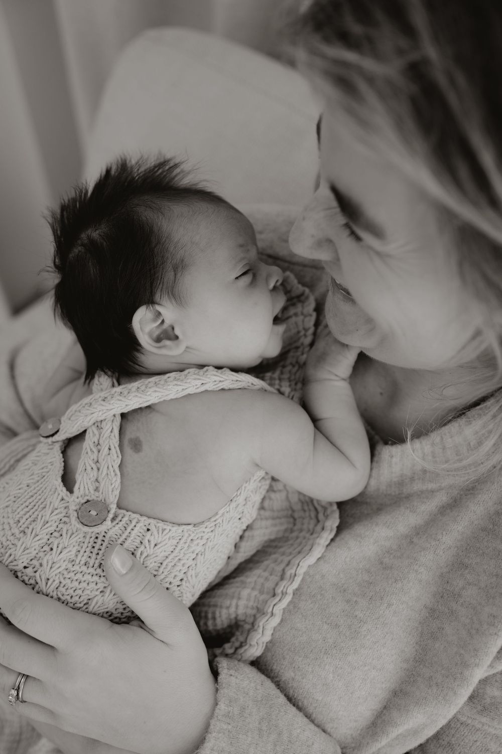 A series of black and white photos showing tender moments between parent and infant in soft, intimate lighting.