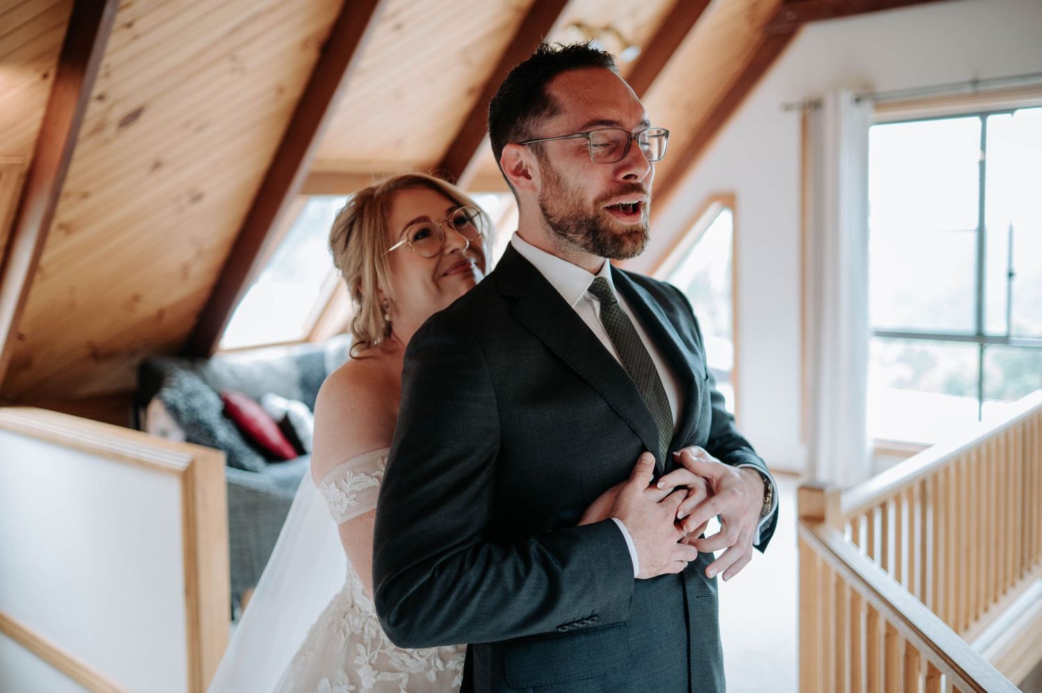 A wedding day moment captured in a rustic attic space with wooden beams.