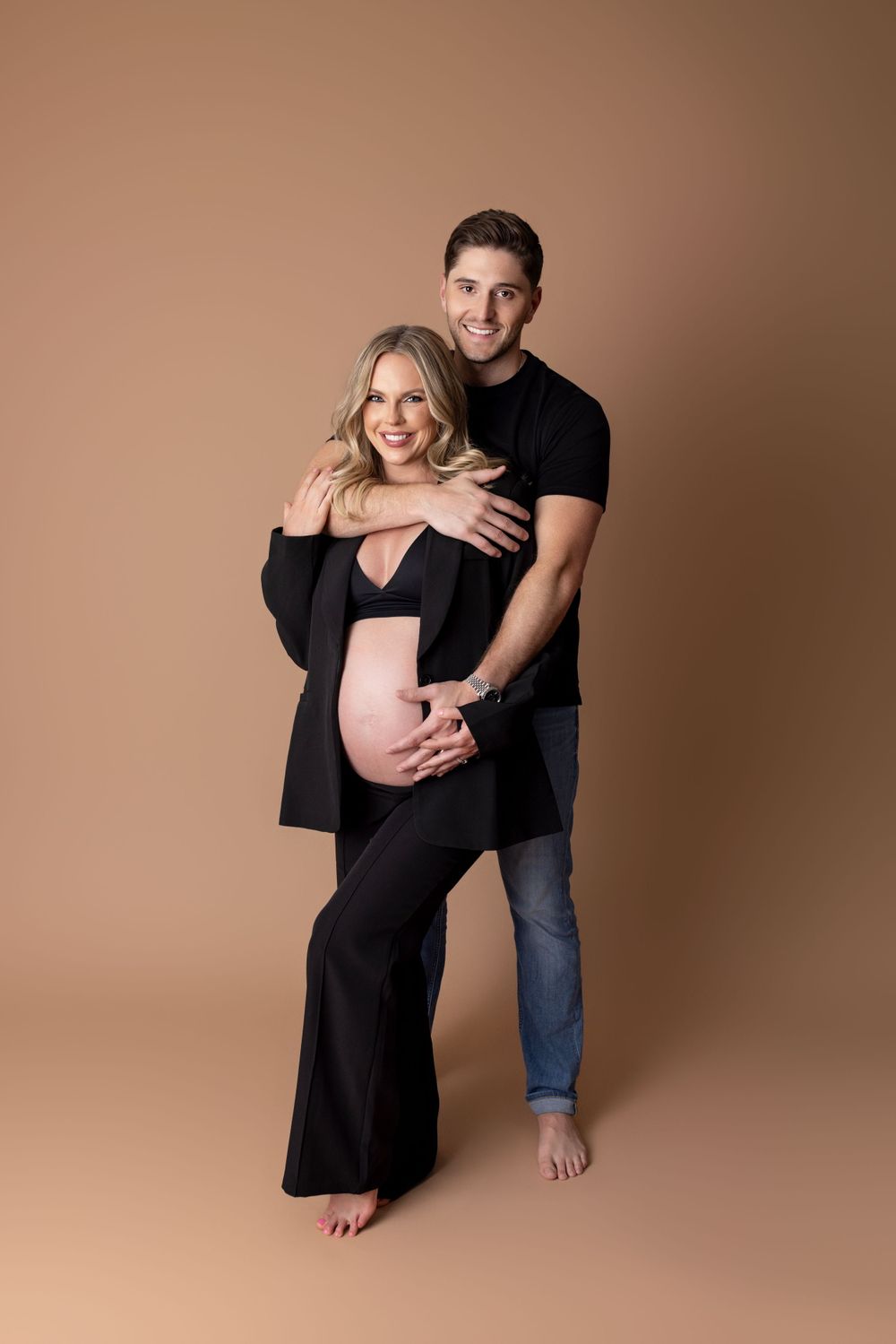 a couple poses embracing each other as they await the arrival of their newborn