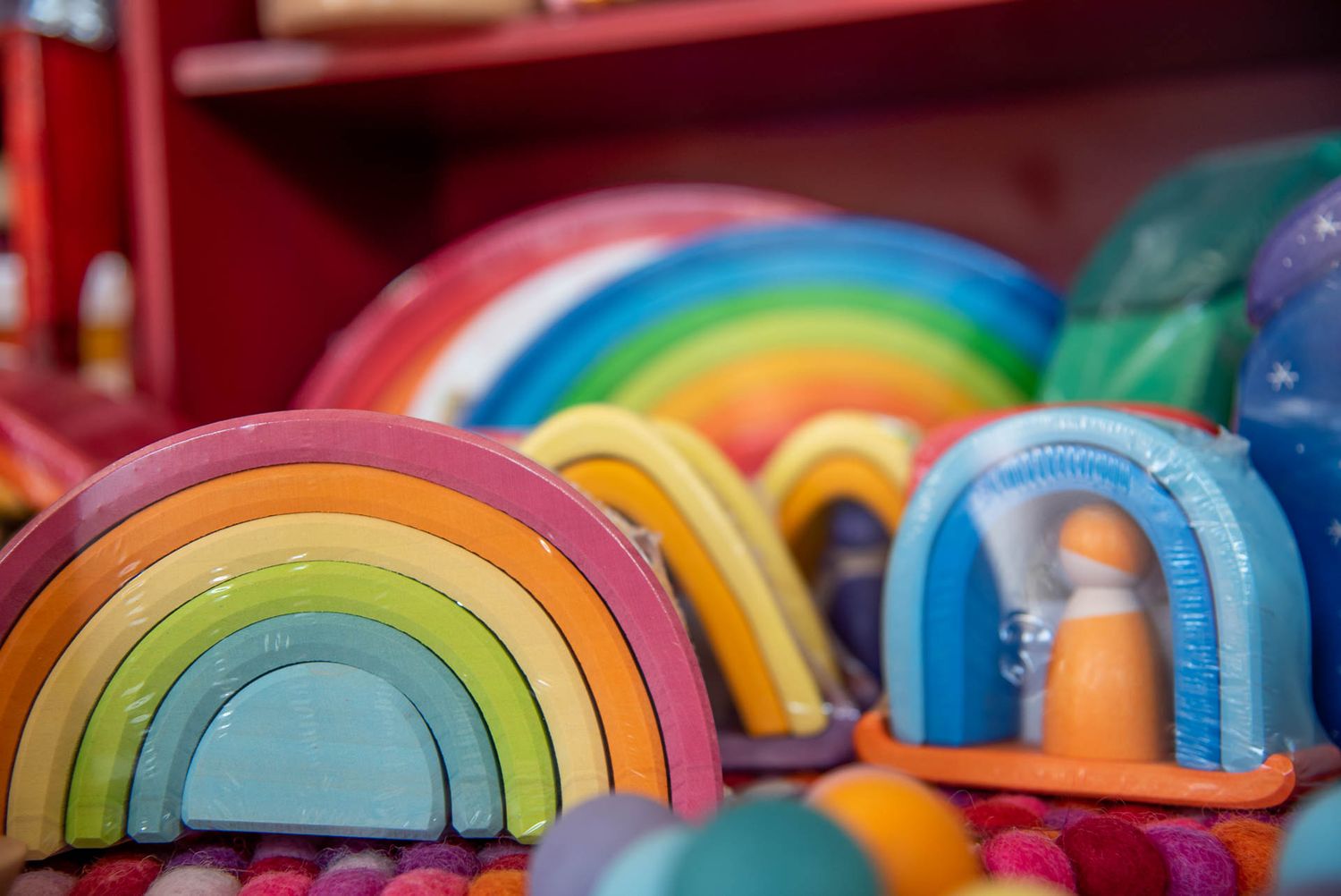 Colorful wooden rainbow stacking toys lined up on display showing vibrant gradient colors from red to blue.
