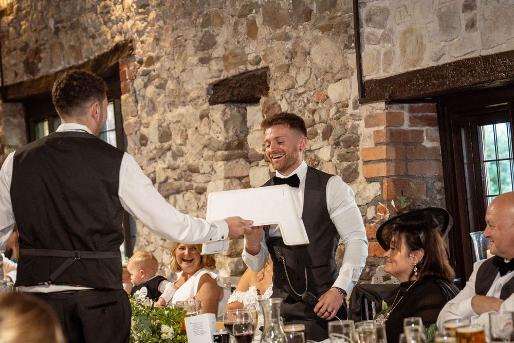 Wedding reception service in progress with waitstaff serving guests in historic stone building.