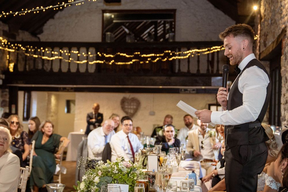 Evening wedding reception with string lights and guests dining in rustic venue.
