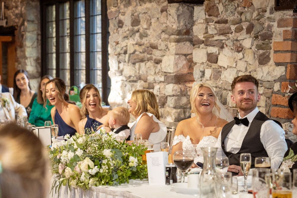 Wedding reception celebration in progress at rustic stone venue with floral centerpieces.