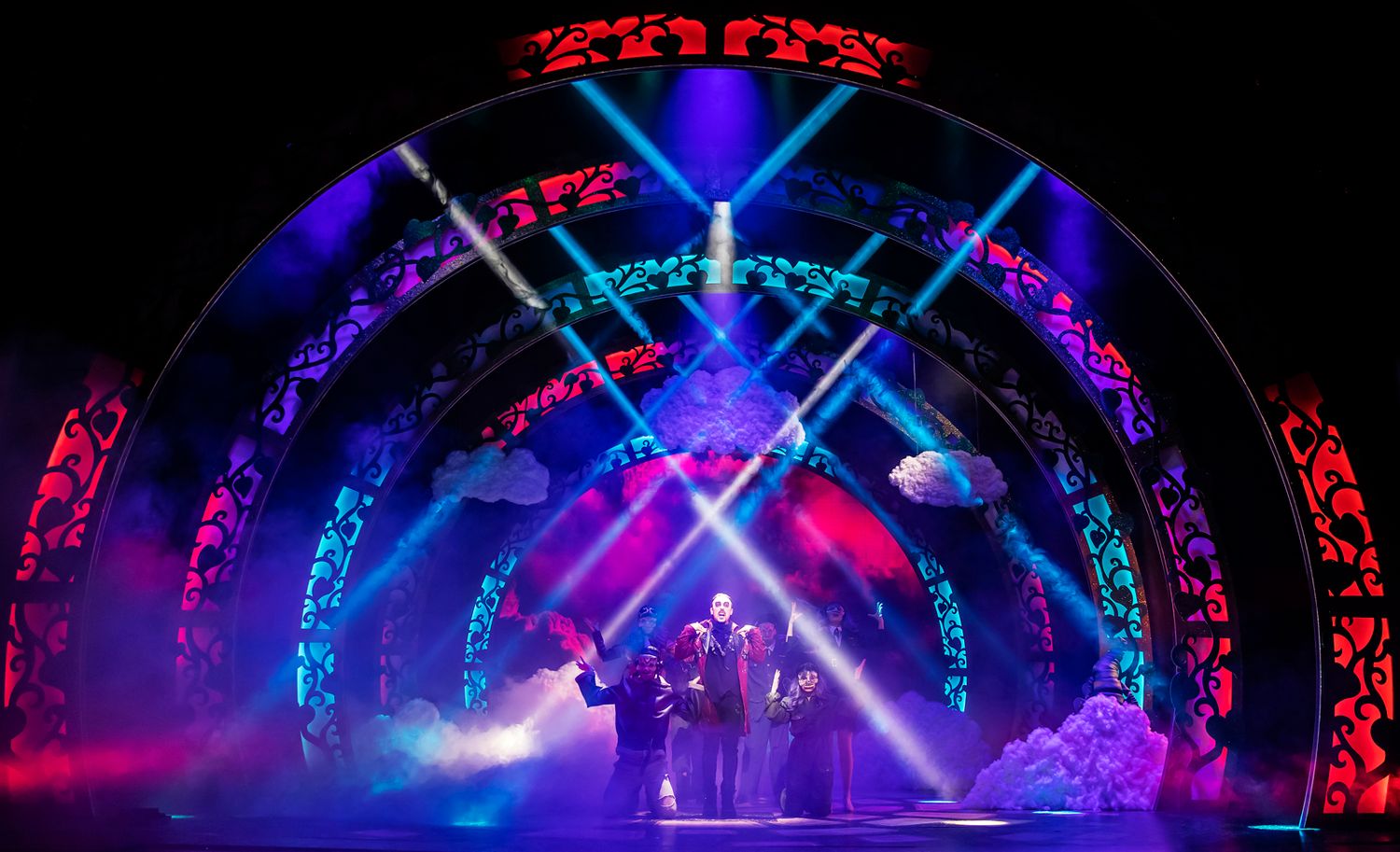 Dramatic stage lighting creates geometric patterns and laser effects for theatrical performance silhouettes.