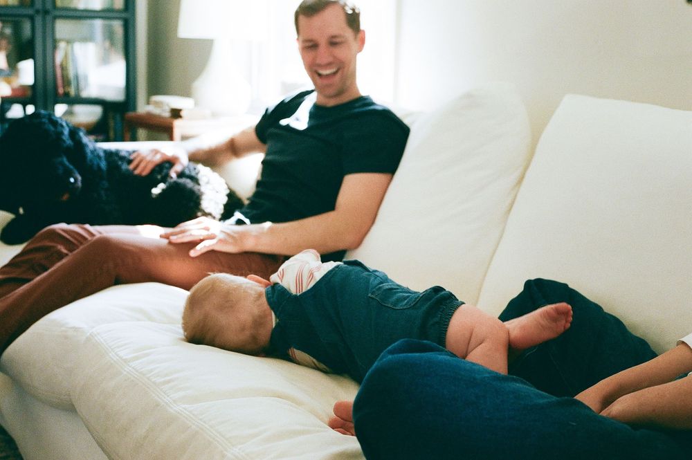 Family sharing playful moment on white sofa with dog.
