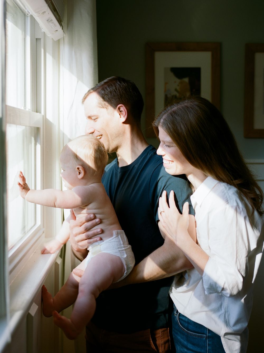 Family gathering by sunny window in cozy home interior.