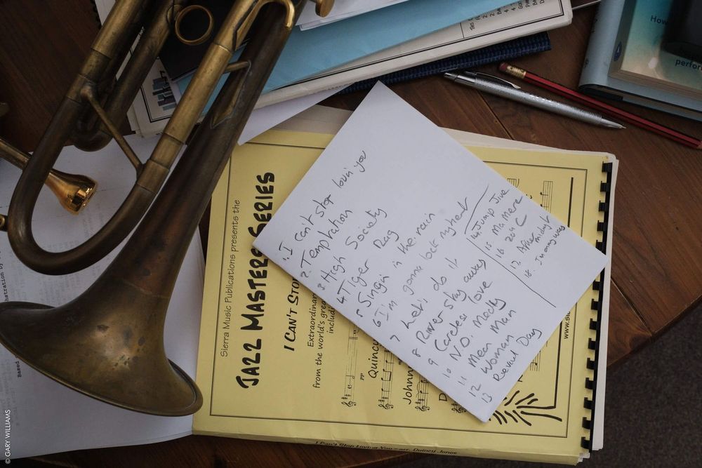 A handwritten note sits on top of a yellow notepad next to brass instruments.