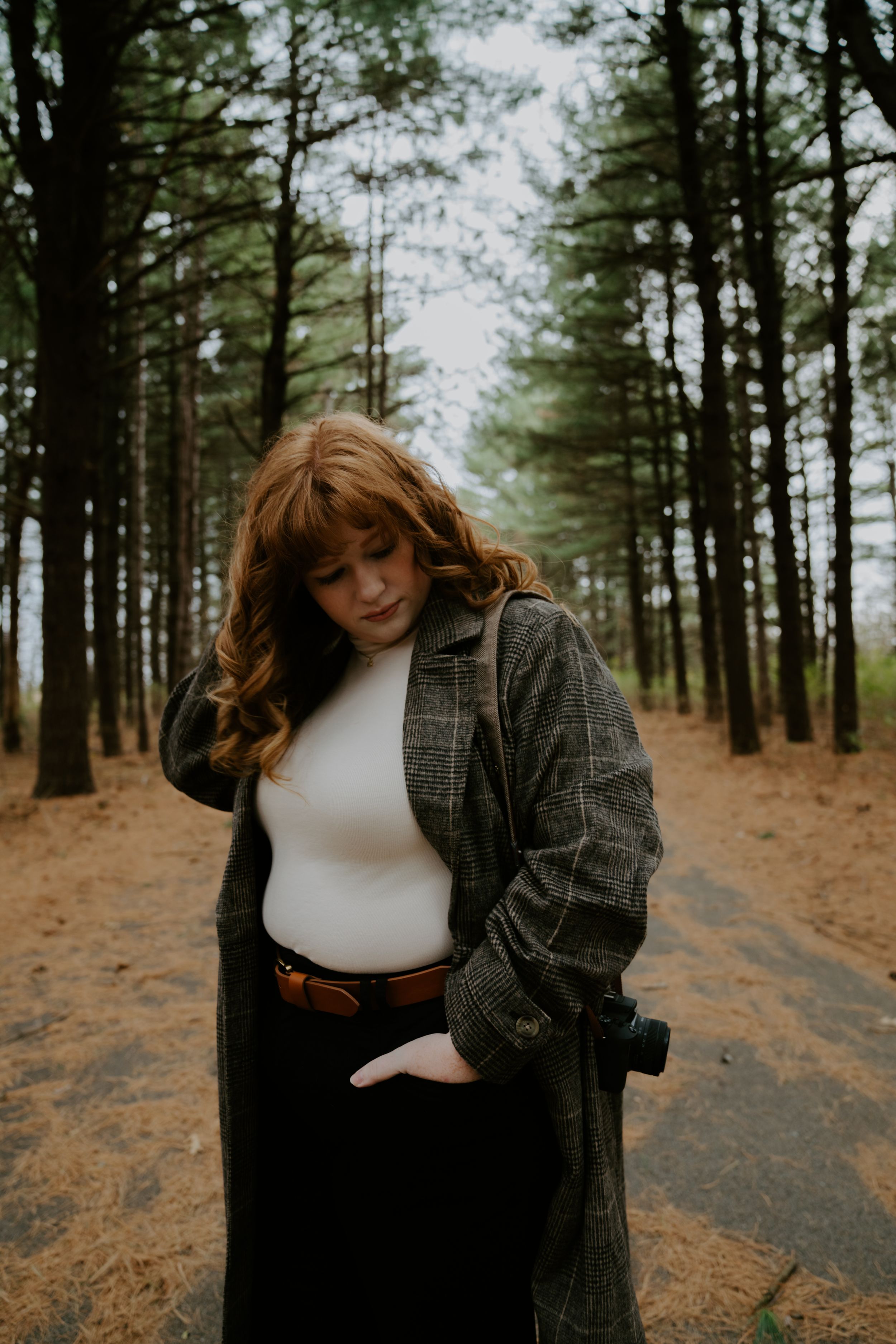 Artistic portrait session among pine trees with someone wearing a gray plaid jacket.