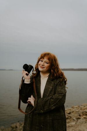 Retro-styled photoshoot with rotary phone by the waterfront on an overcast day.