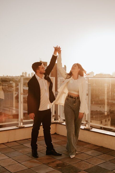 Couple dancing together on rooftop terrace during golden hour sunset.