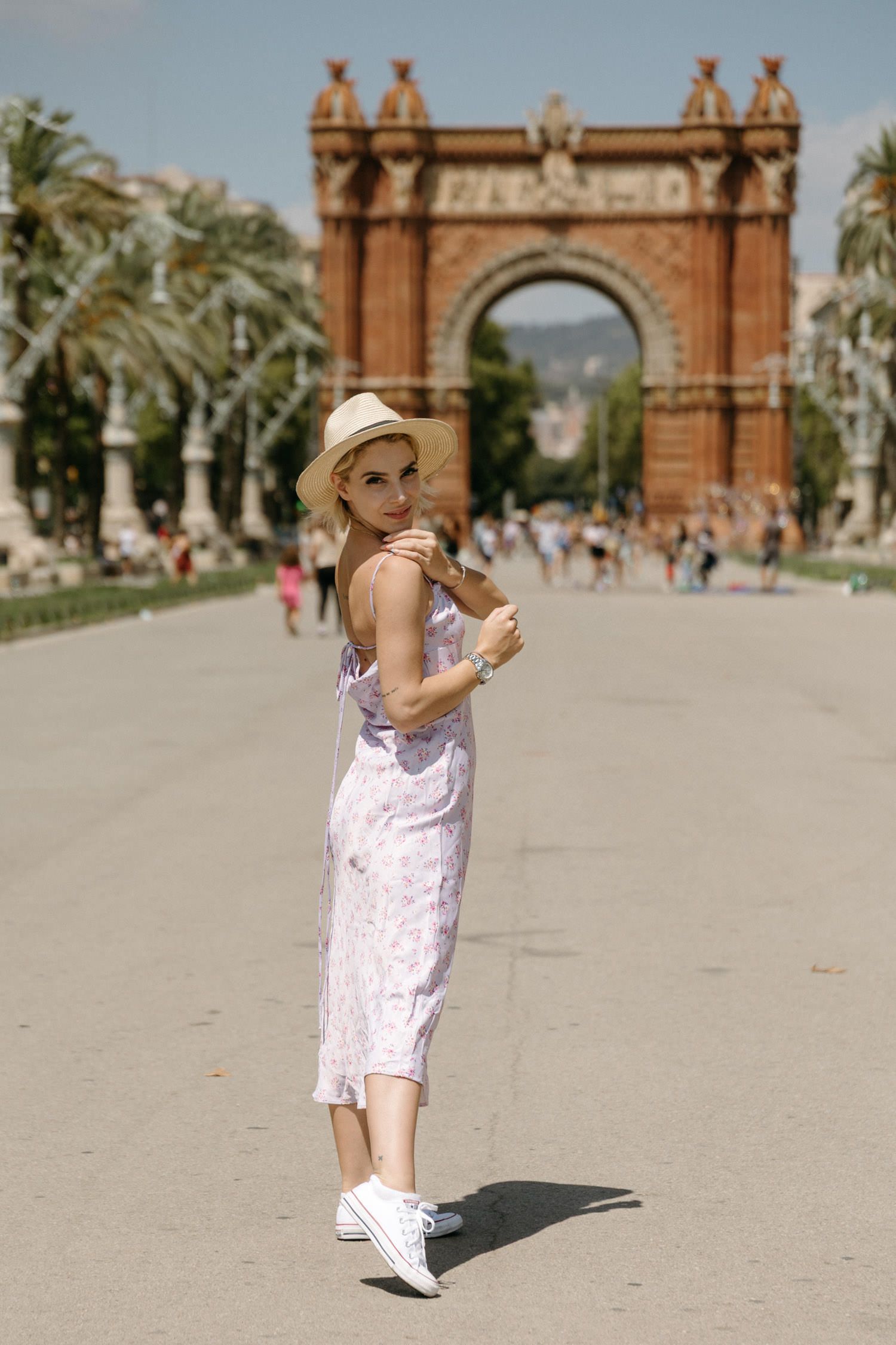 Dancing in a white dress near the Arc de Triomf in Barcelona with palm trees in the background.