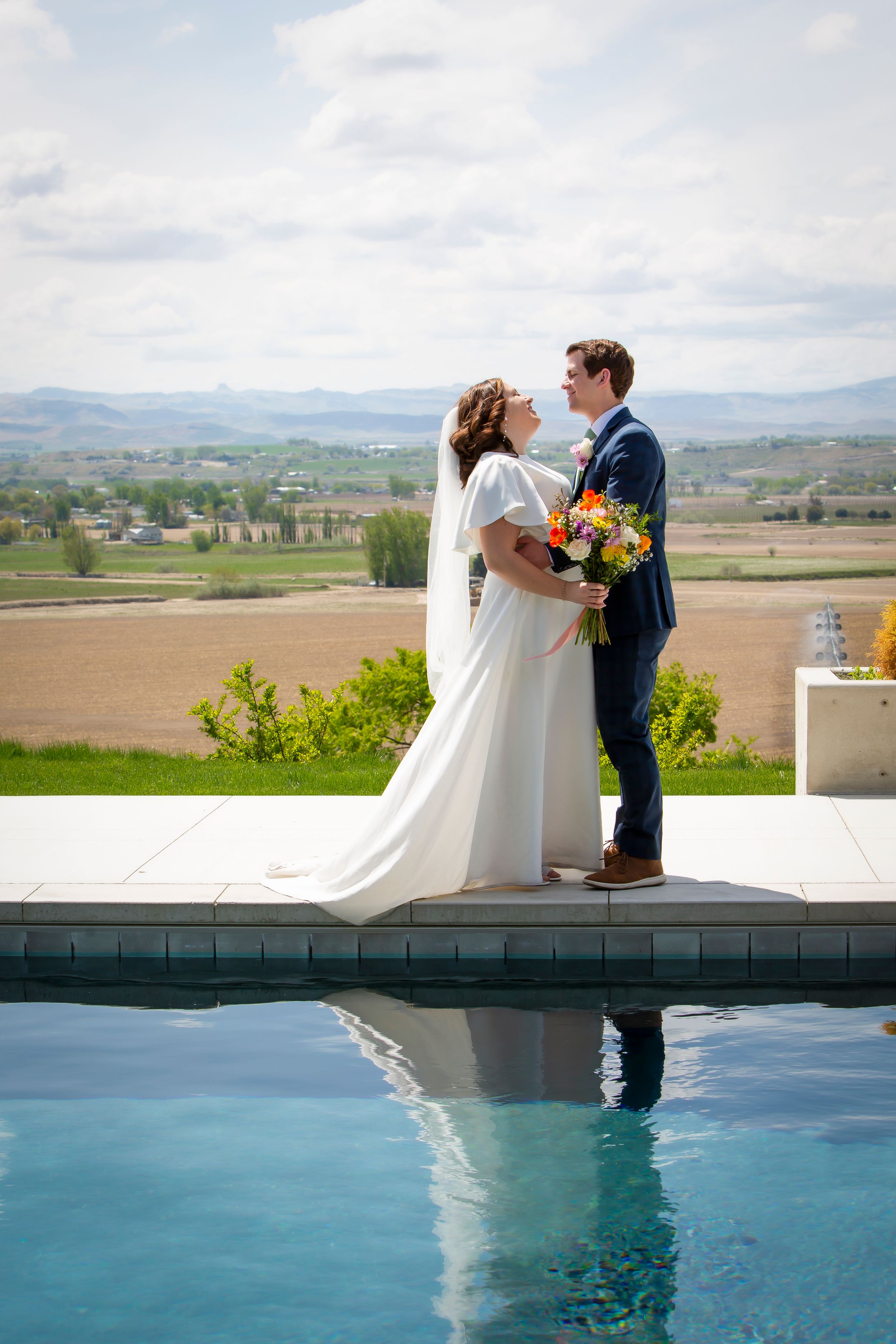 bride and groom embracing near pool with reflection and views of the valley at Garman Hill Wilder, Idaho
