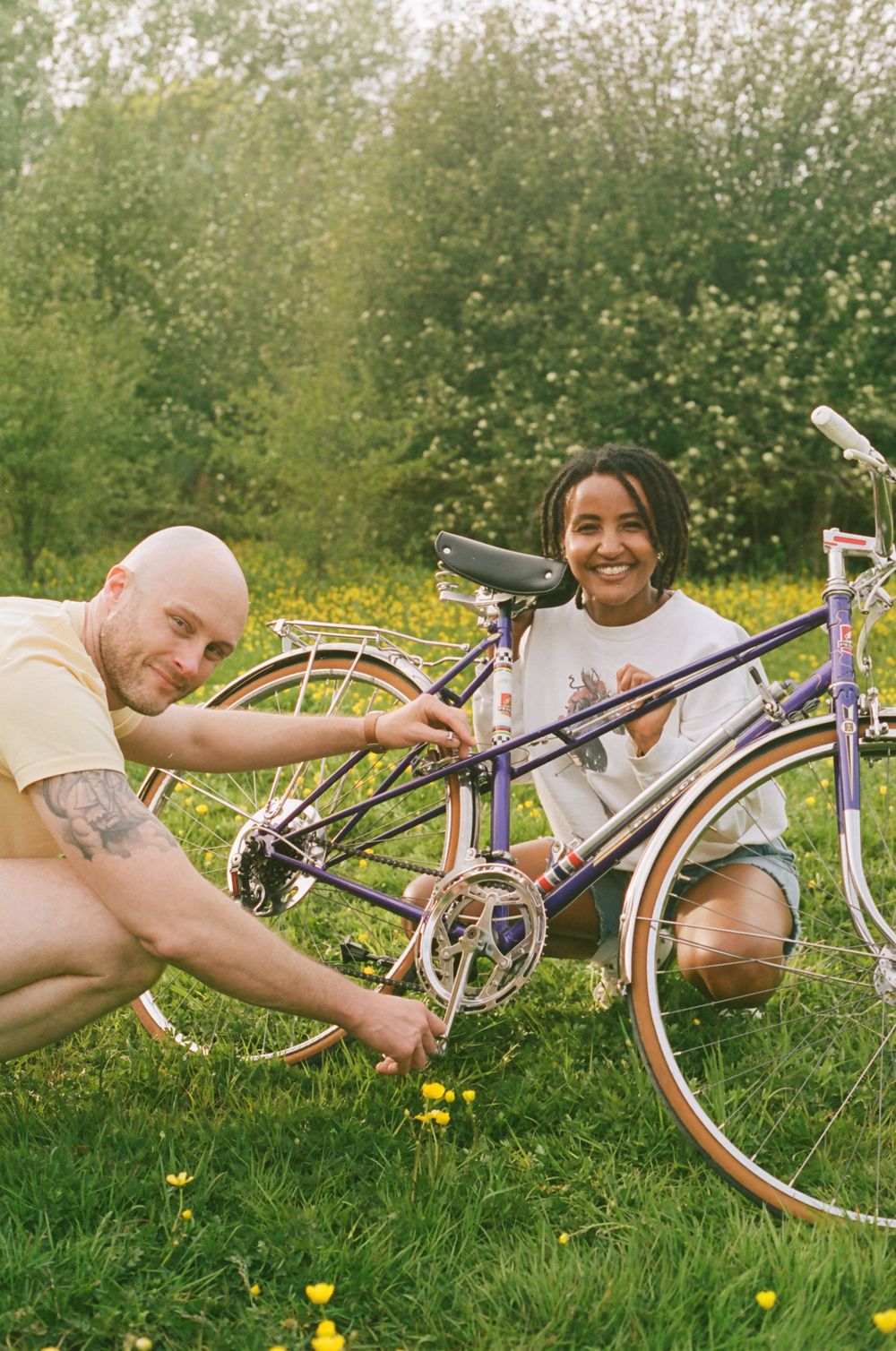 Two people lying in a grassy field with bicycles on a sunny summer day.