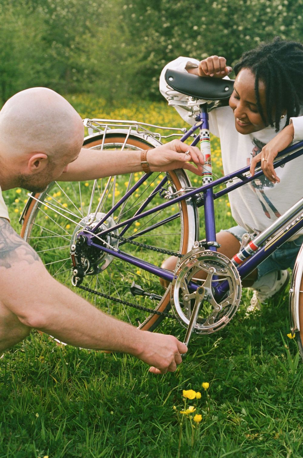 Close-up shots of hands working on bicycle parts in green grass.