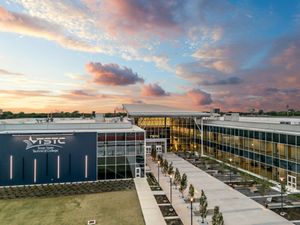 Aerial view of TSTC campus building at sunset with dramatic colorful sky and modern glass architecture.