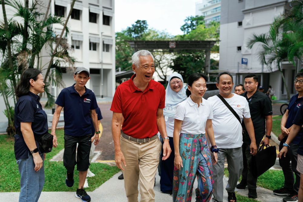 Group of people walking together through a tropical courtyard area with palm trees and buildings in Singapore.