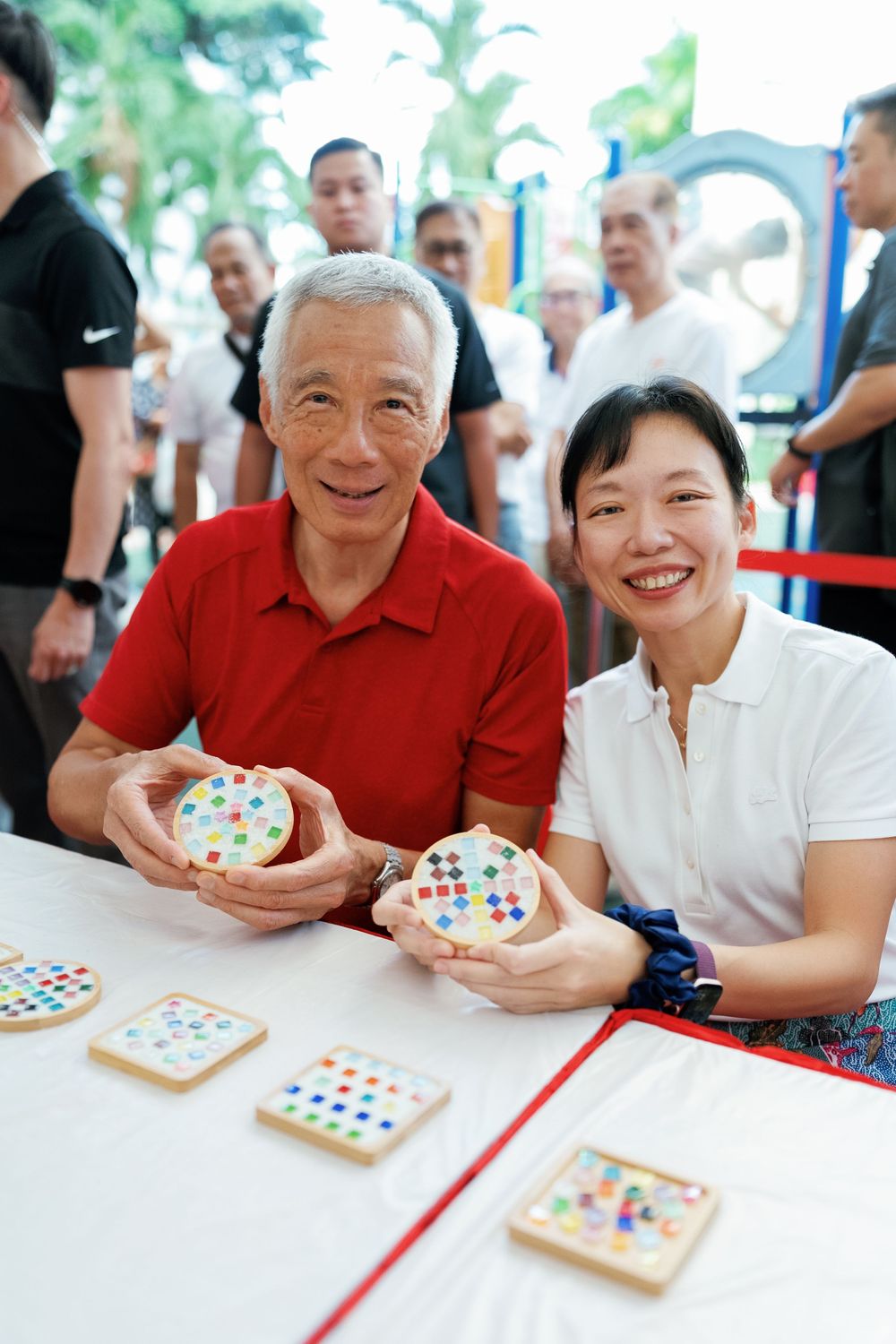 Two people decorating square sugar cookies with colorful candies and smiling at a table.