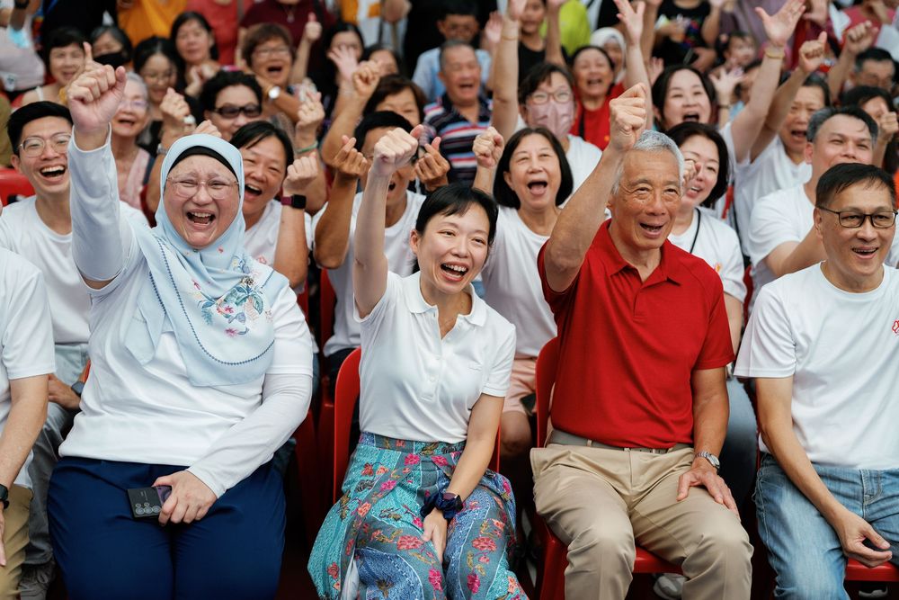 Large crowd of excited spectators reacting with joy and laughter while watching an event.