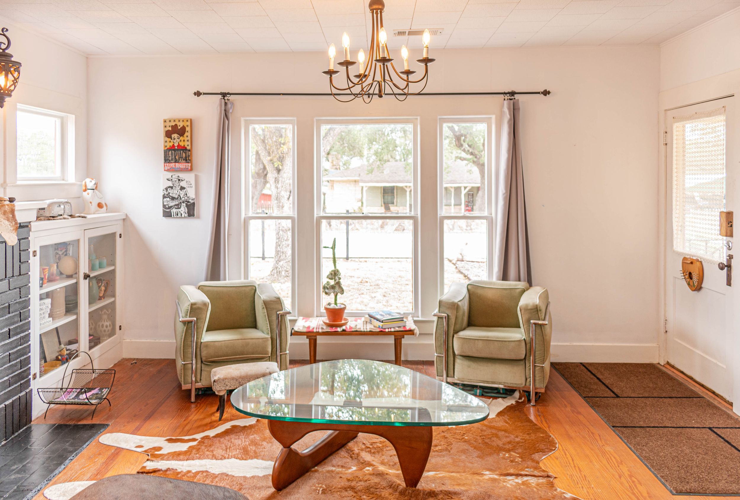 Bright living room with hardwood floors, chandelier, and multiple seating areas in neutral tones.