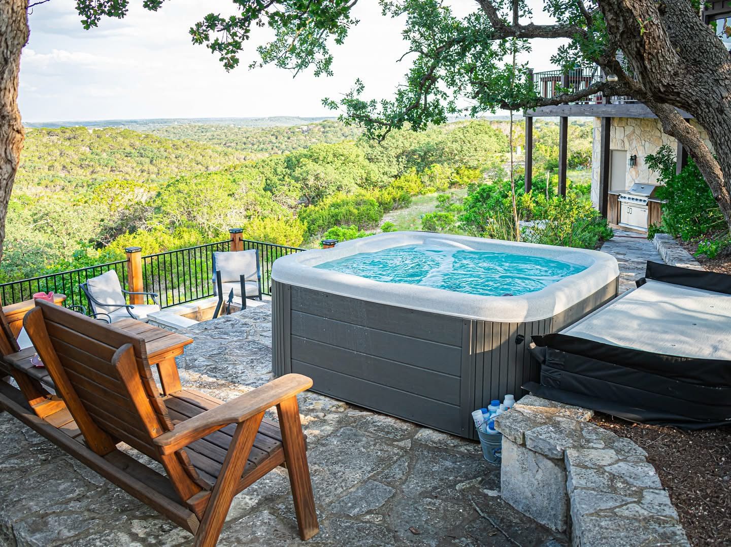 Outdoor deck with hot tub and lounge chairs overlooking scenic hill country views.