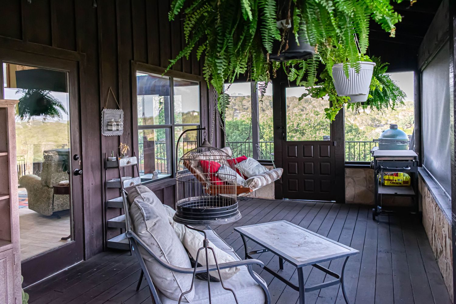 Covered outdoor porch with comfortable seating and hanging ferns creating a relaxing atmosphere.