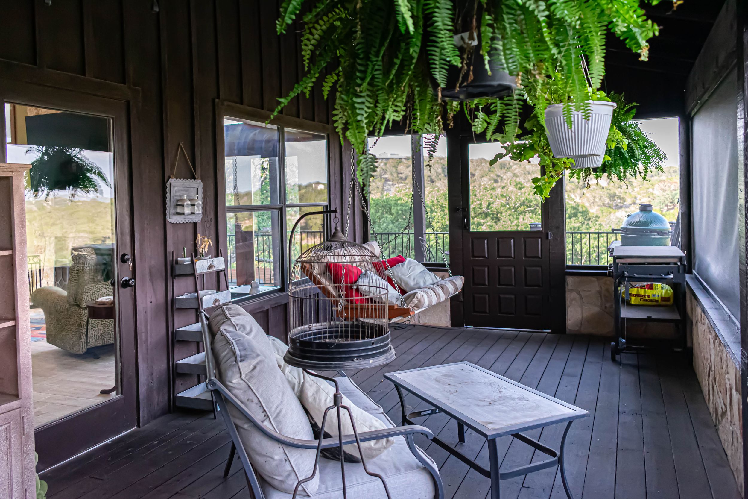 Covered outdoor porch with comfortable seating and hanging ferns creating a relaxing atmosphere.