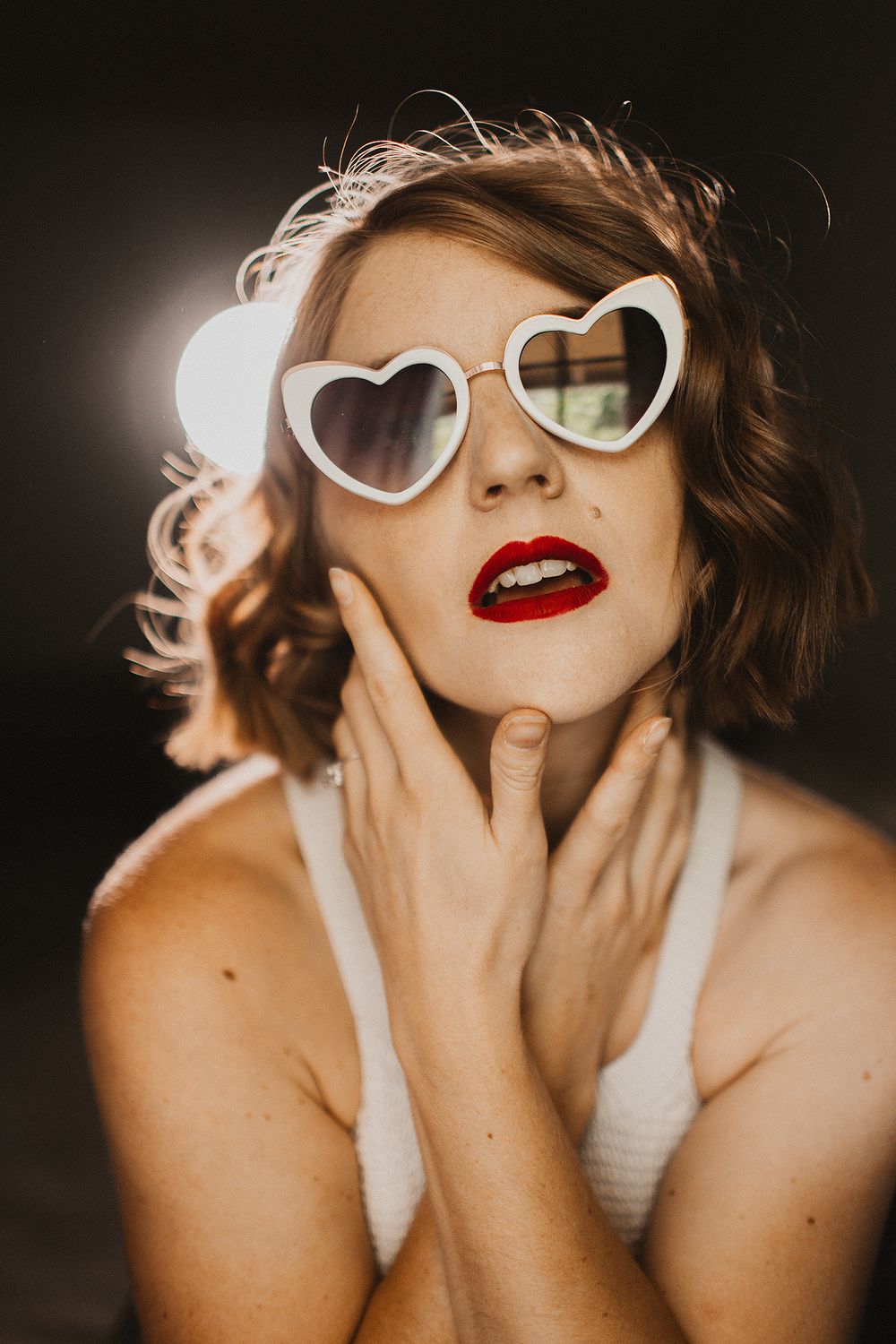 Fashion portrait series featuring retro white cat-eye sunglasses and bold red lipstick in dramatic lighting.