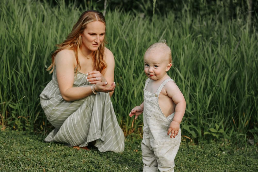 Mother and baby share tender moments together outdoors in a lush green meadow setting.