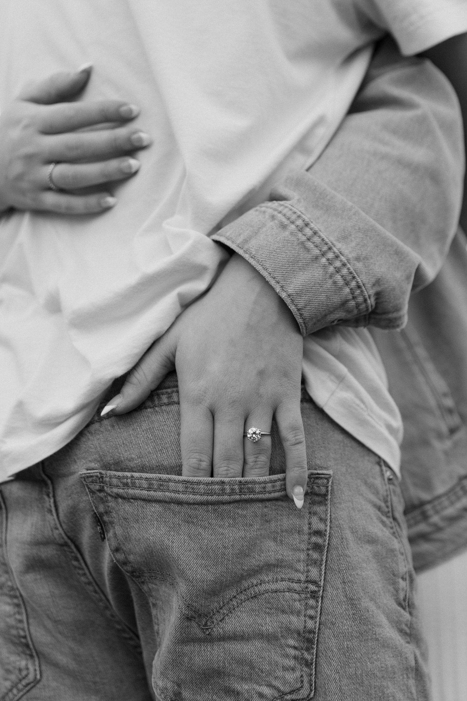 Newly engaged Olivia shows off engagement ring with her hand in her Fiance's back pocket.