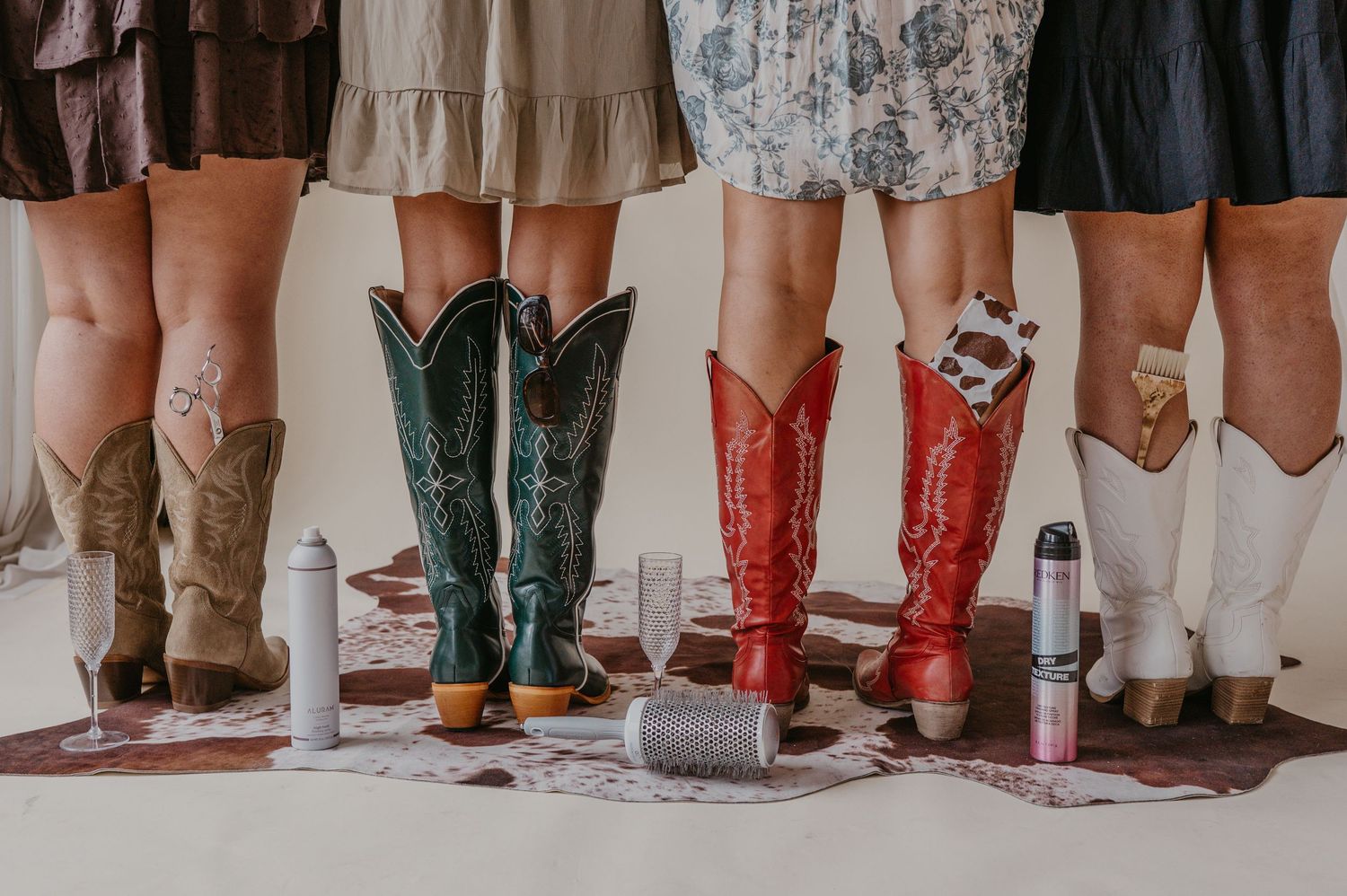 A group of four women in cowgirl boots with carefully placed cosmetology tools representing their hair salon's brand