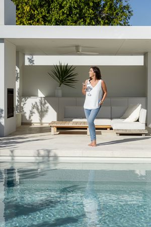 Someone stretches on a modern poolside deck with crystal clear turquoise water in a minimalist outdoor setting.