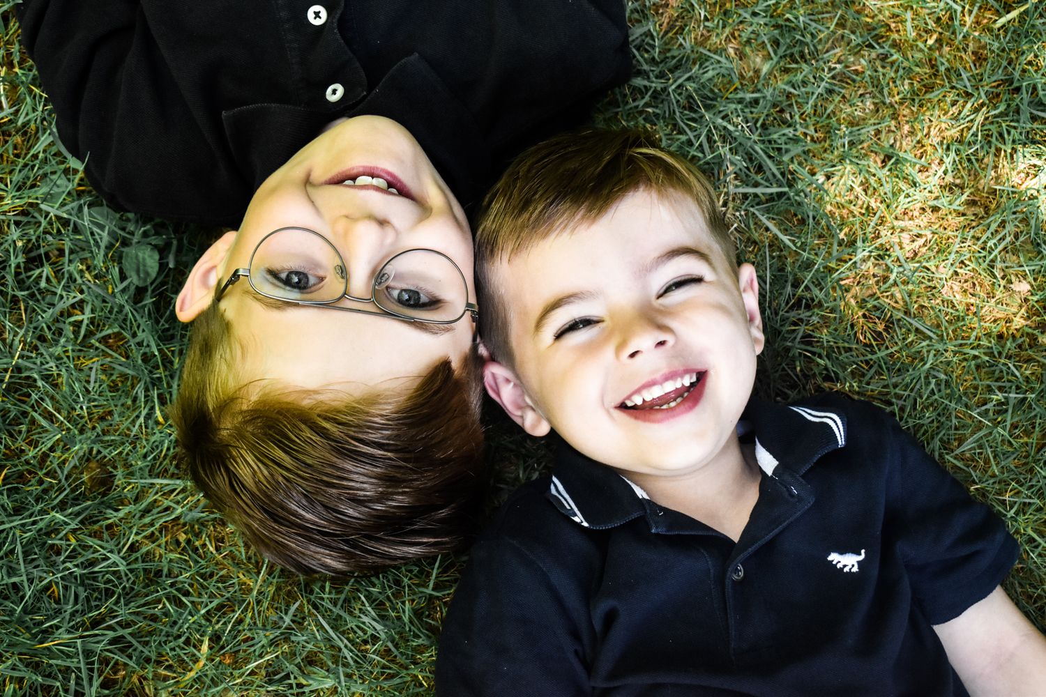 Candid family photos showing joyful expressions while lying in grass outdoors.