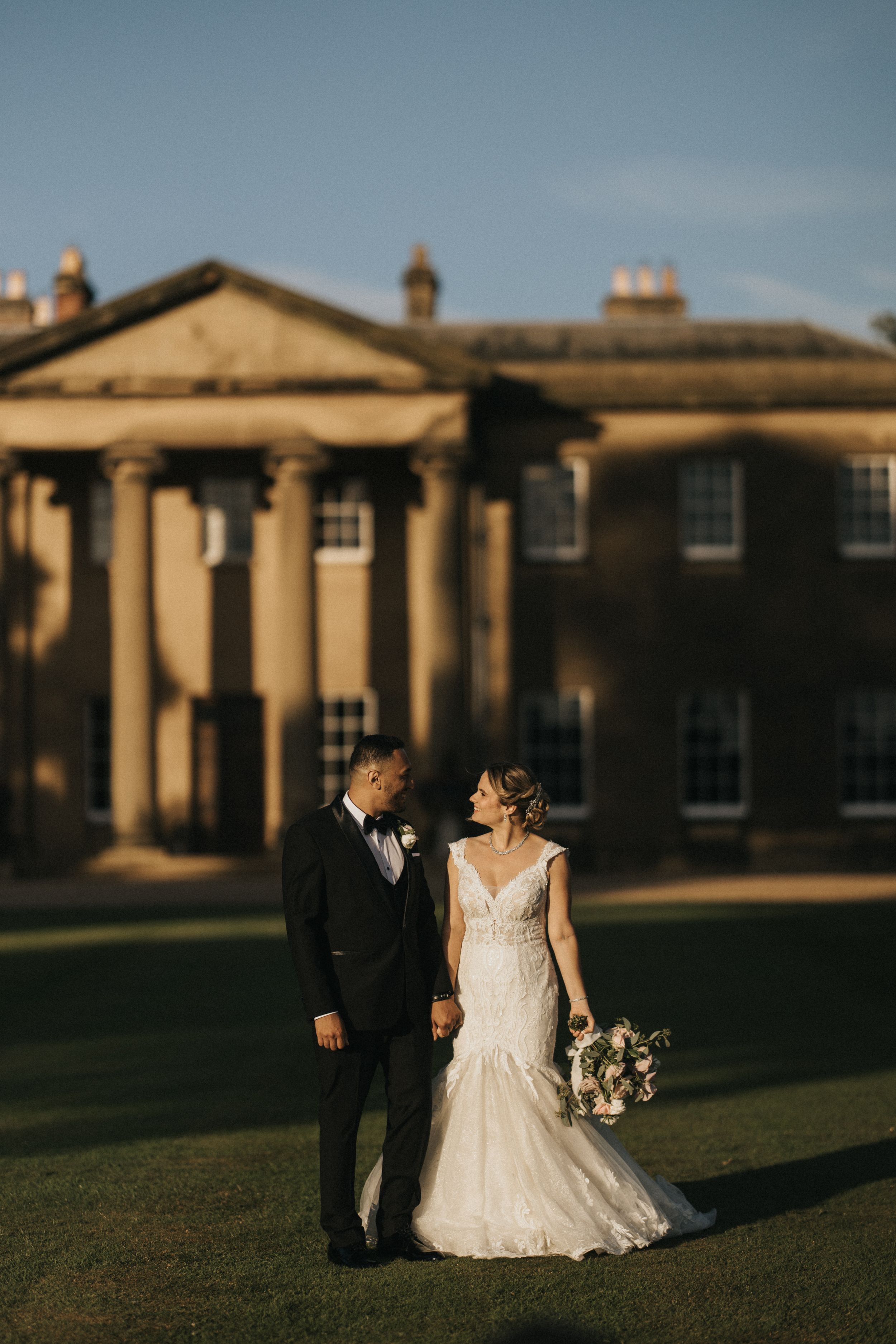 A couple in wedding attire poses in front of Rise Hall at sunset. Image taken by Grimsby photographers.