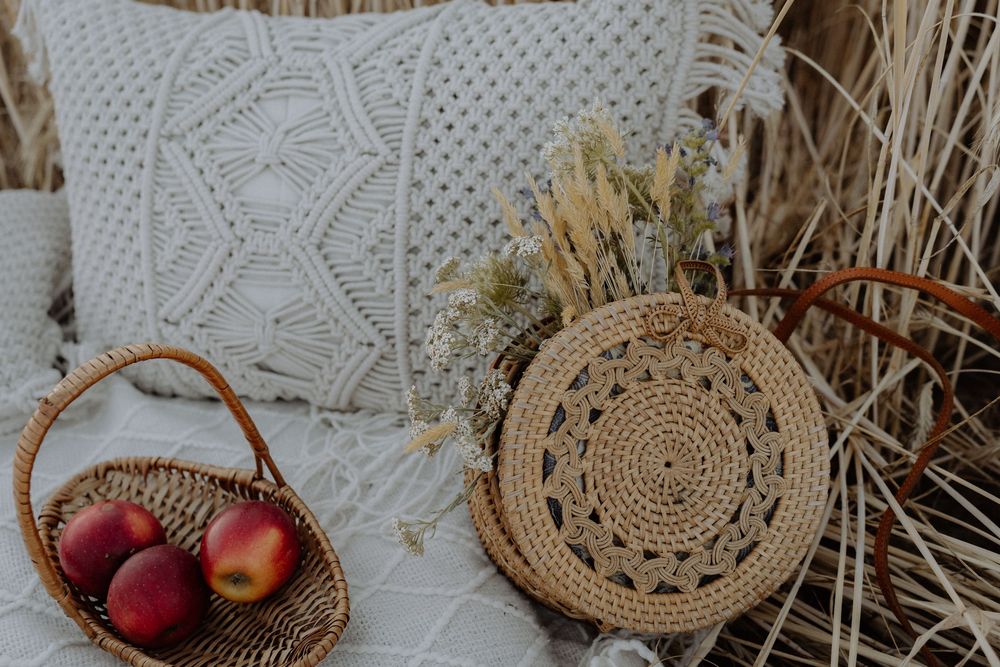 Cozy bohemian decor with macrame pillow, woven basket placemats, and fresh apples in a rustic wicker basket.