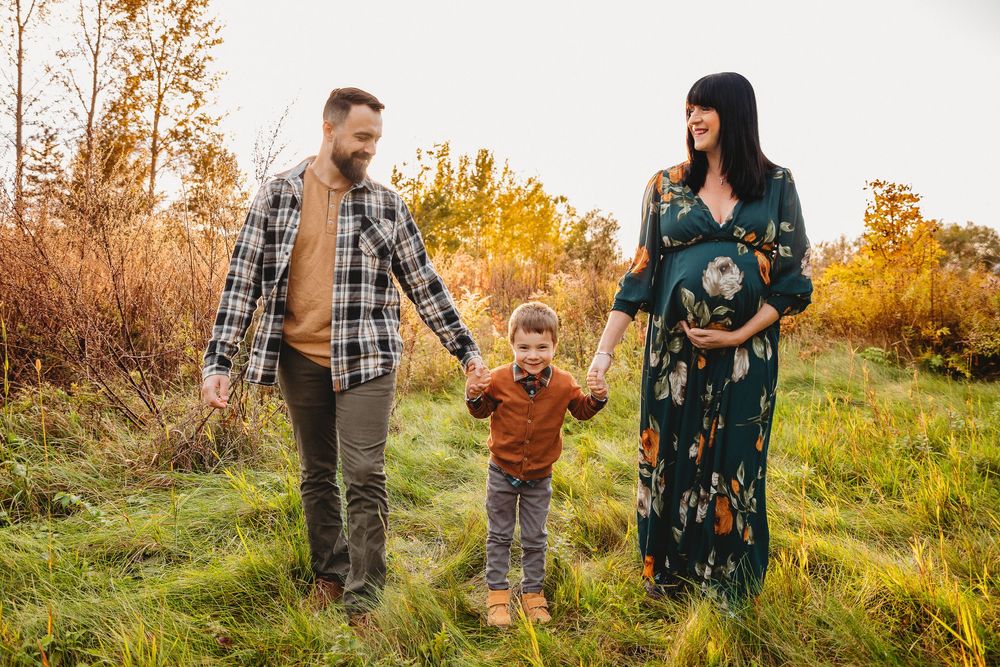 Family walking together through tall grass in autumn field at sunset.