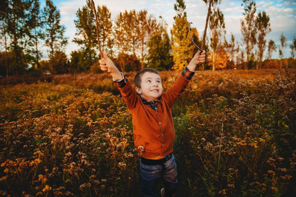 Child jumping with excitement in field of wildflowers during golden hour.