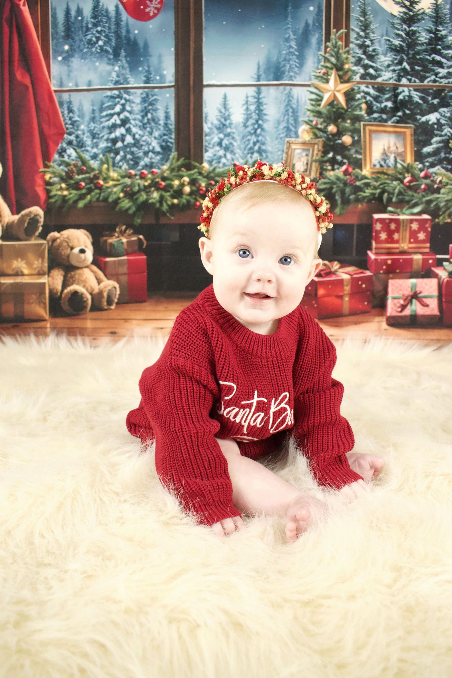 Baby in red sweater crawling on white fur rug with Christmas decorations in background.
