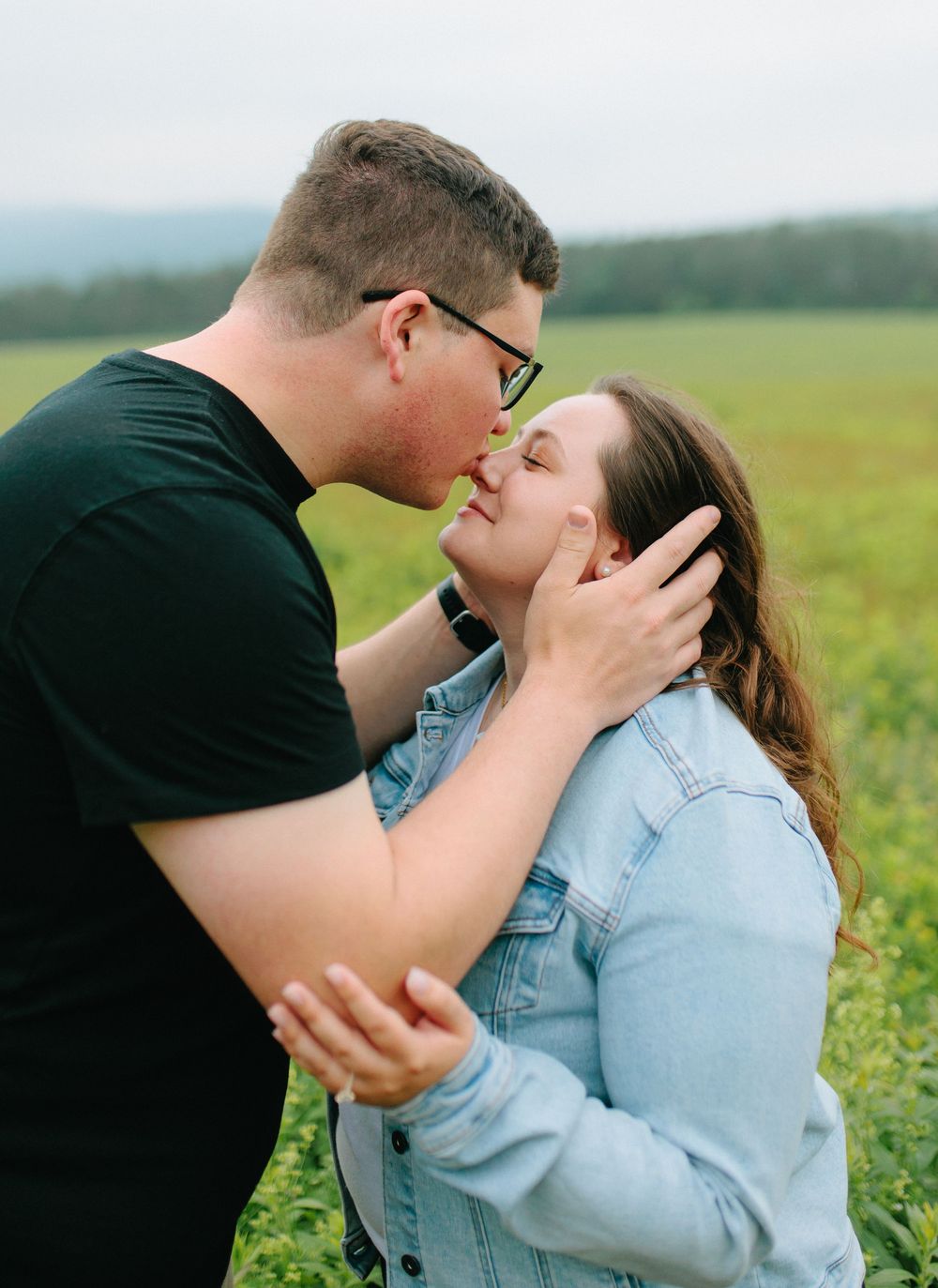 A romantic moment between a couple sharing a tender embrace in a green meadow on a sunny day.