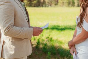 A couple exchanges vows during an outdoor wedding ceremony in a sunlit meadow.