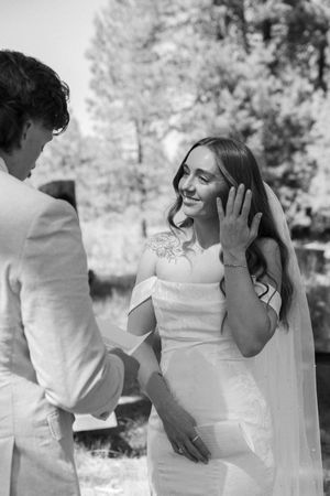 A tender wedding first look moment captured in black and white photography outdoors.