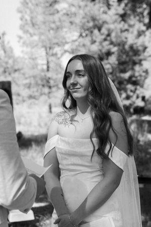 Black and white candid shot of a bride's joyful reaction during an outdoor wedding celebration.