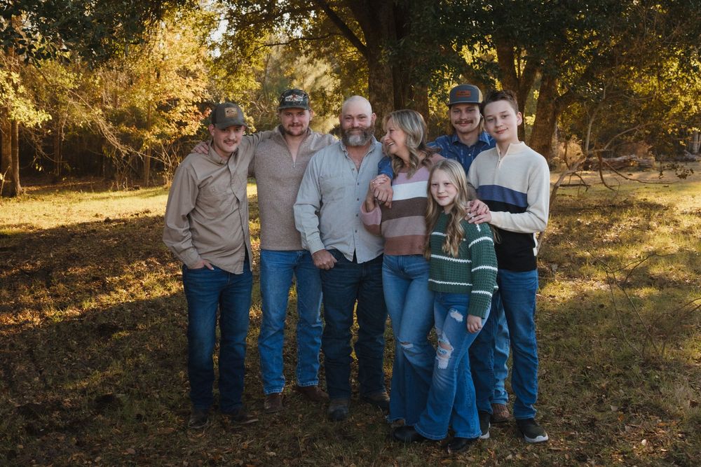 A group stands together outdoors in casual clothing on an autumn day with golden sunlight filtering through trees.