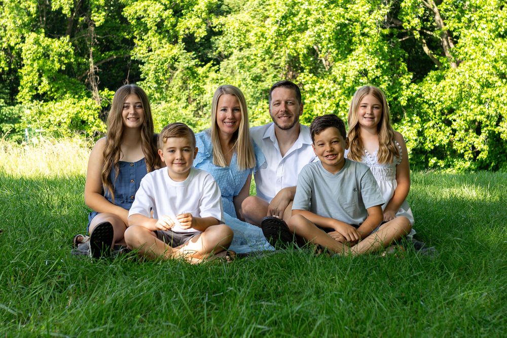 Family group lying in green grass during summer photoshoot.