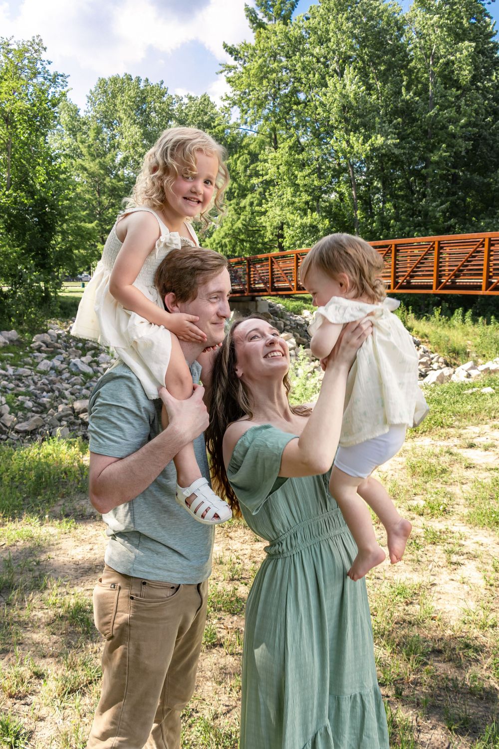 Candid family moments captured in a natural setting with coordinated green and neutral clothing.