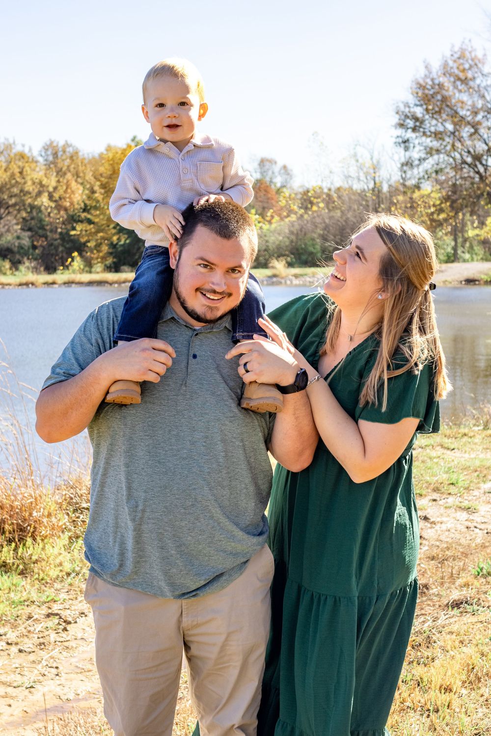 Candid family photos taken by a lake during golden hour with autumn colors in background.