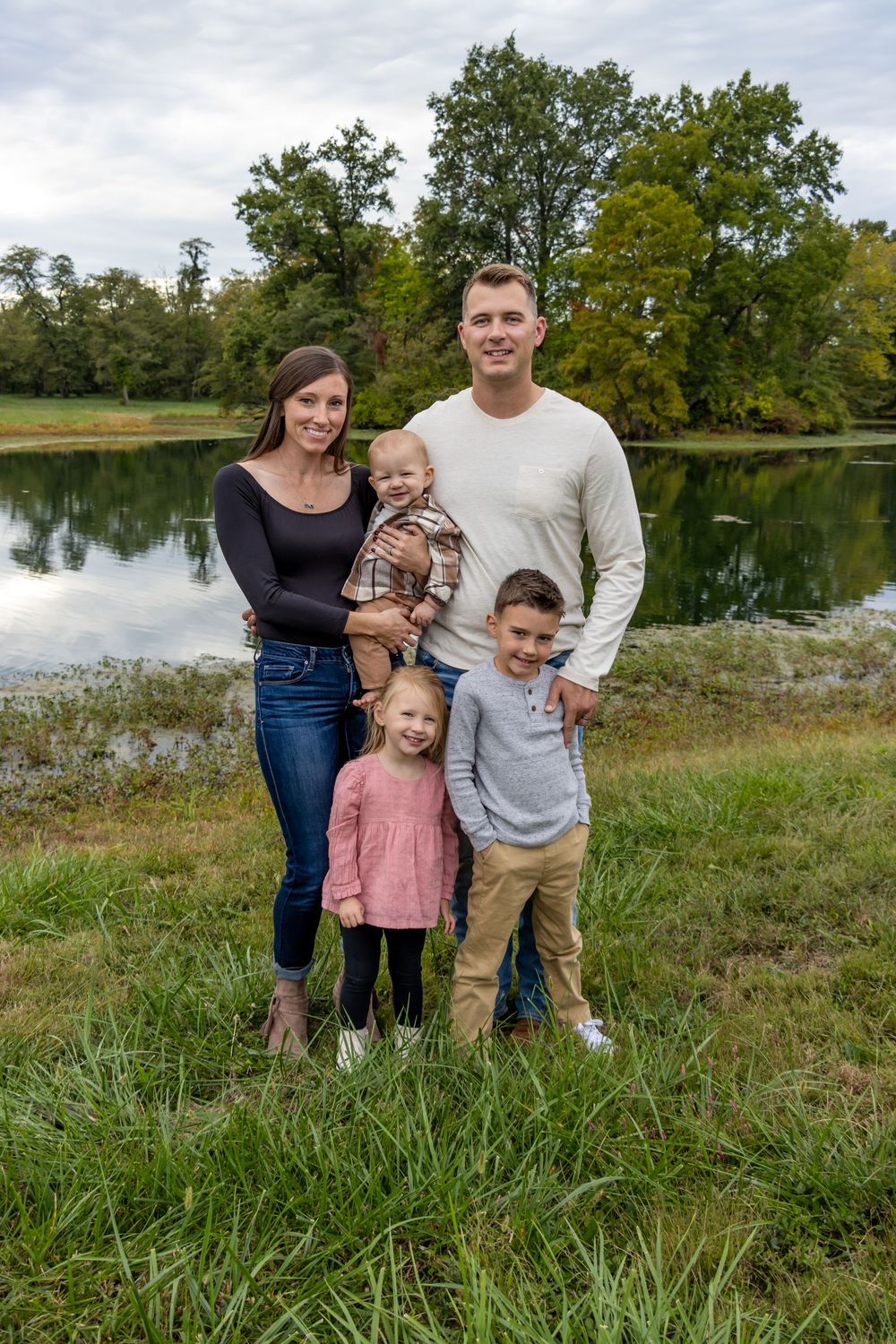 Family gathering by a peaceful pond on an autumn day.