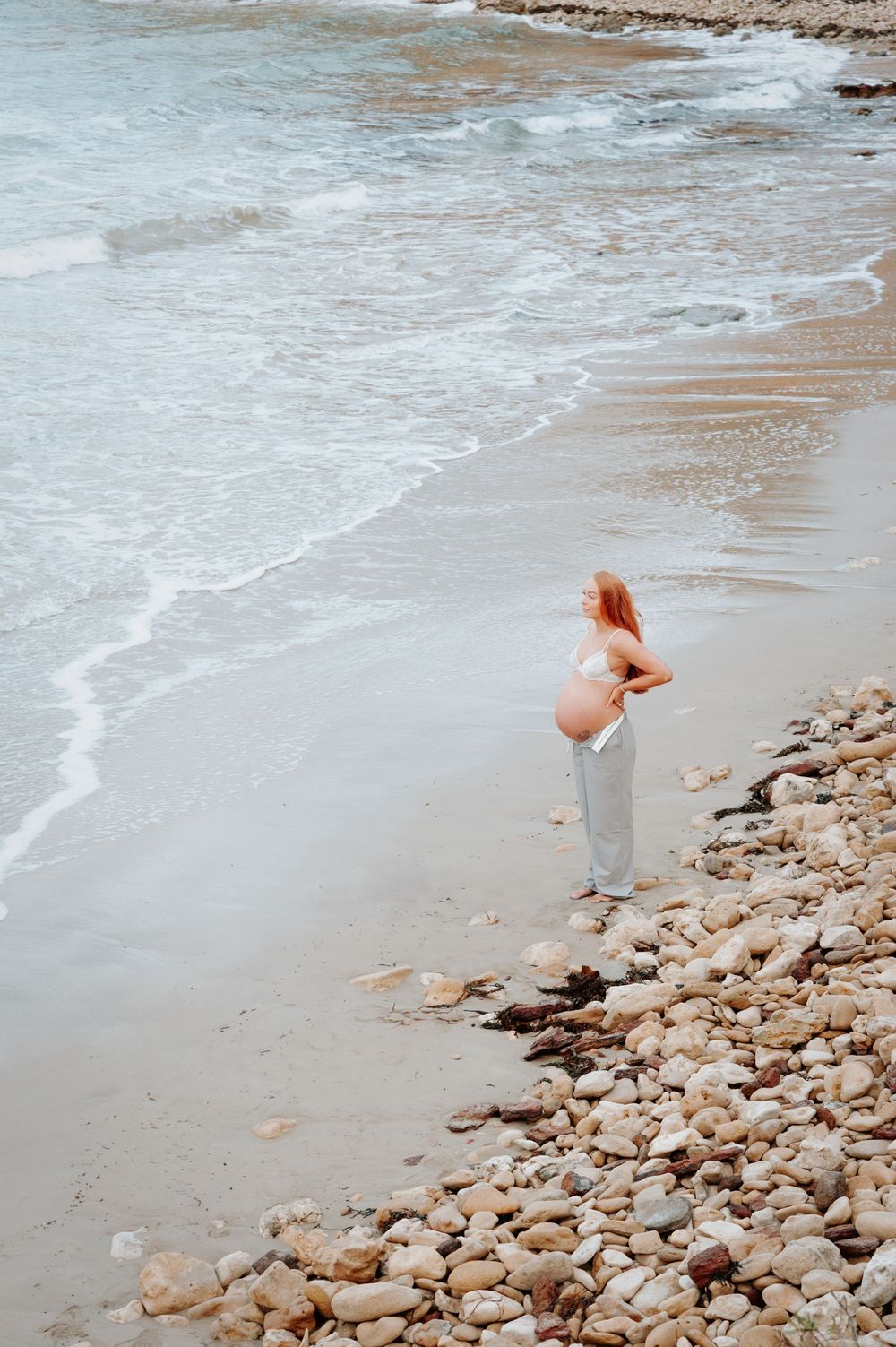 Person walking along rocky shoreline with waves lapping at the beach.
Altona Family Photographer Melbourne