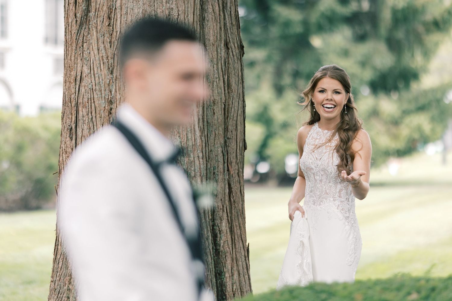 A couple shares a candid first look moment in a garden setting, with the bride in a beautiful lace gown.